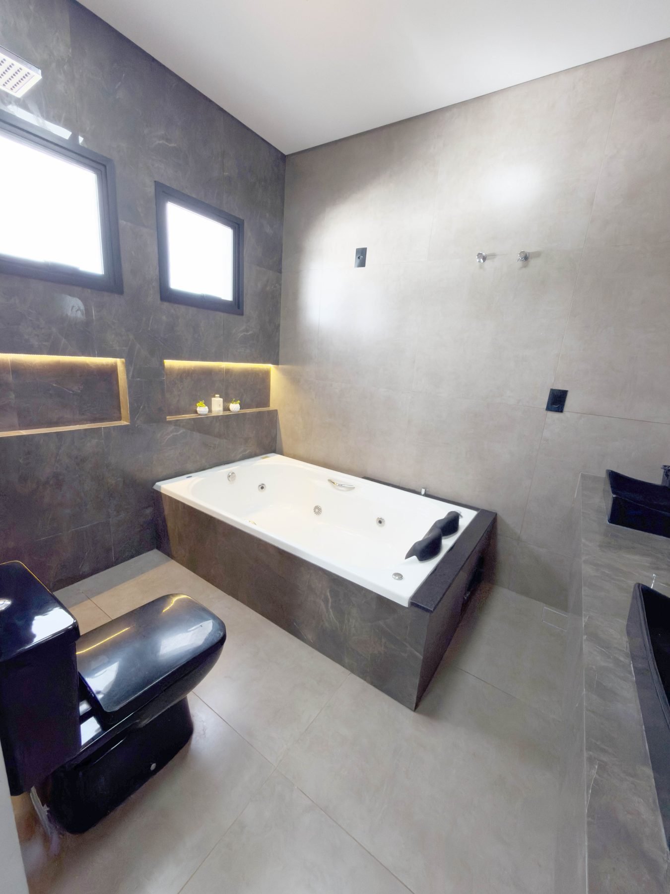 Banheiro da suíte com banheira de hidromassagem e nichos iluminados