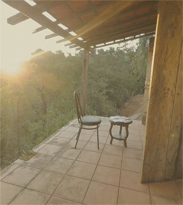 Varanda coberta com vista para a vegetação ao redor, ao entardecer
